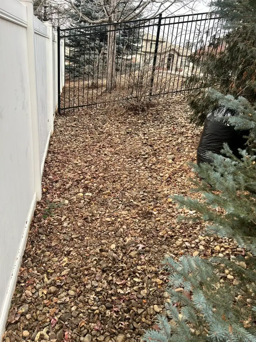 Rock landscaping bed installed along a vinyl fence line in Colorado