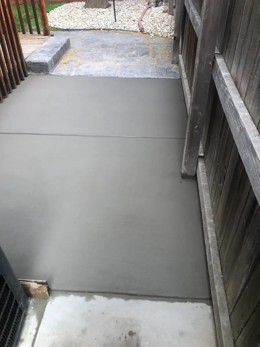 Freshly poured and finished concrete patio slab beside a wood fence in Denver, Colorado